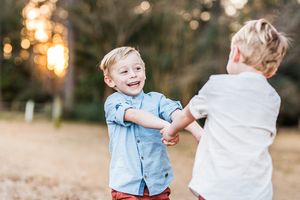 two twin boys in a field wearing zara clothes playing ring around the rosie