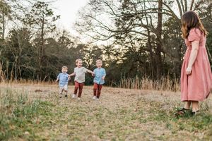 three toddler boys running in a field